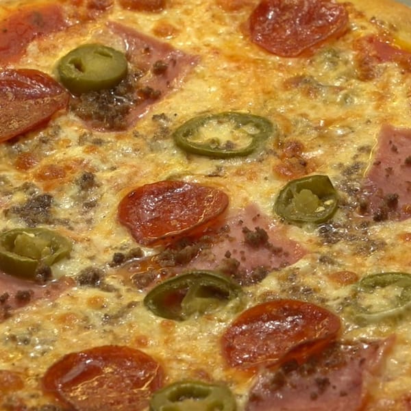 Close-up of a hot Italia Express pizza with pepperoni, ham, ground beef, and jalapeños.